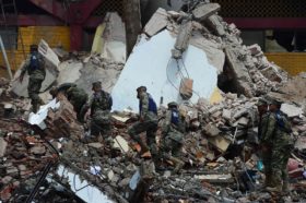 Mexican Navy members walk amid debris of the Town Hall building which